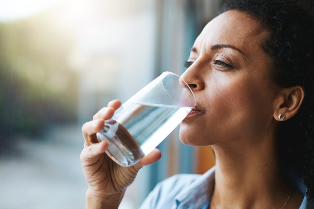 Kobieta pijąca w domu wodę z dystrybutora